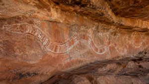 Longue figure de serpent peinte en argile blanche et ocre rouge sur une paroi de grès abritée, dans le nord de l’Australie
