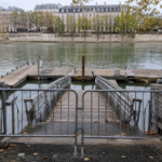 Ponton de baignade au bord d’un fleuve urbain, barrière fermée en travers de la rampe d’accès, aucun baigneur.