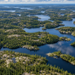 Vue aérienne d’une mosaïque de petits lacs sombres semés dans la forêt boréale et les affleurements de granite du Bouclier canadien.