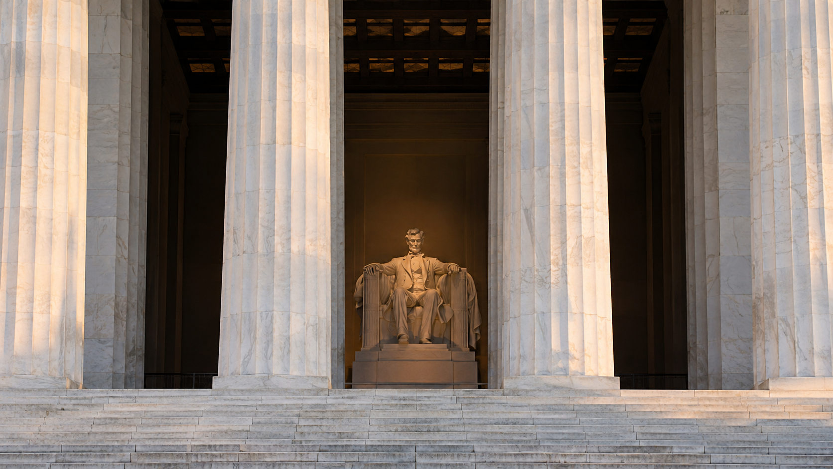 Un mémorial néoclassique à colonnes blanches, une statue assise visible dans la pénombre entre deux fûts.