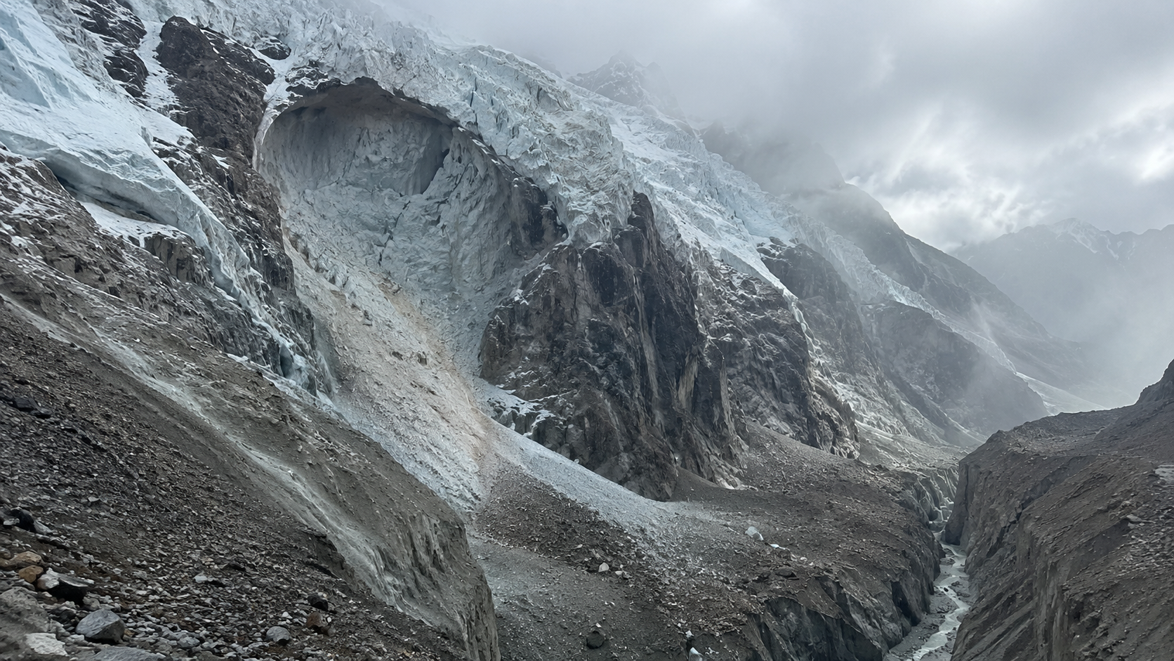 Paroi glaciaire de haute altitude au-dessus d’une gorge étroite, avec une cicatrice fraîche de glace et de roche détachées.