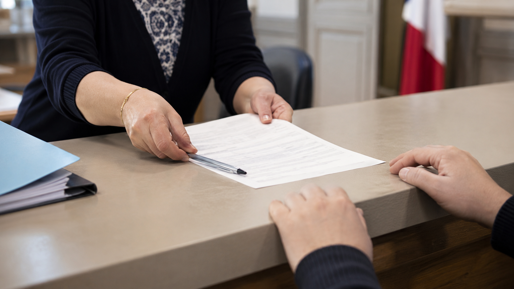 Les mains d’un agent d’état civil poussant un formulaire et un stylo vers celles d’un usager, au comptoir d’une mairie française.