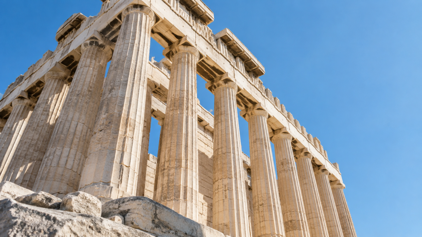 Colonnes cannelées de marbre d’un temple grec antique vues en contre-plongée sous un ciel clair.
