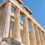 Colonnes cannelées de marbre d’un temple grec antique vues en contre-plongée sous un ciel clair.