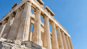 Colonnes cannelées de marbre d’un temple grec antique vues en contre-plongée sous un ciel clair.