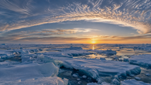 Banquise arctique à l’aube sous une vaste bande nuageuse d’altitude incurvée au-dessus du pôle.