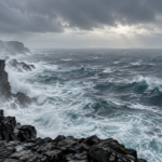 Une houle grise et un ciel bas au-dessus de l’océan, vus depuis une falaise de basalte battue par les embruns.