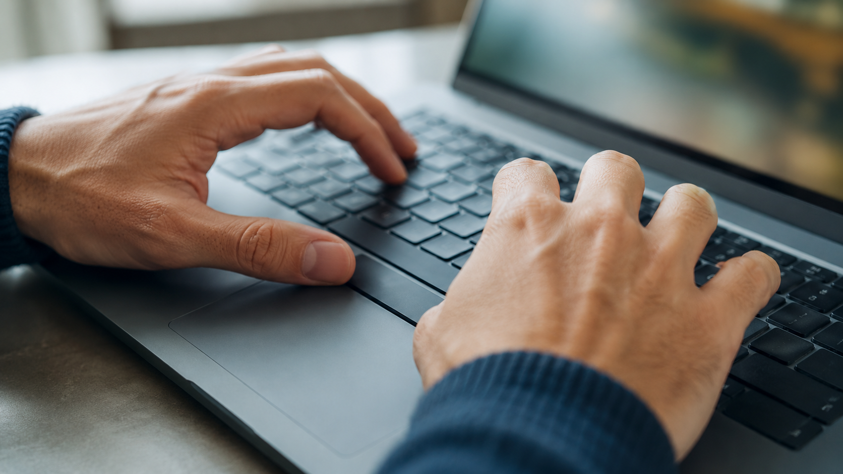 Gros plan sur deux mains d’adulte posées sur un clavier d’ordinateur portable, le pouce appuyant sur la barre d’espace.