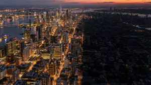 Vue aérienne au crépuscule d'une grande ville dont la moitié des quartiers est éclairée et l'autre plongée dans le noir.