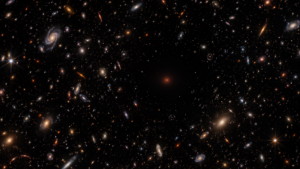 Ciel profond semé de minuscules galaxies, avec une zone sombre où brille une faible lueur isolée