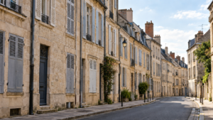Une rangée d’immeubles de pierre aux volets fermés borde une rue déserte de centre-ville de province.