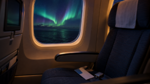 Hublot d’un long-courrier de nuit, une aurore polaire visible au-dessus de l’océan, un siège vide avec une carte d’embarquement