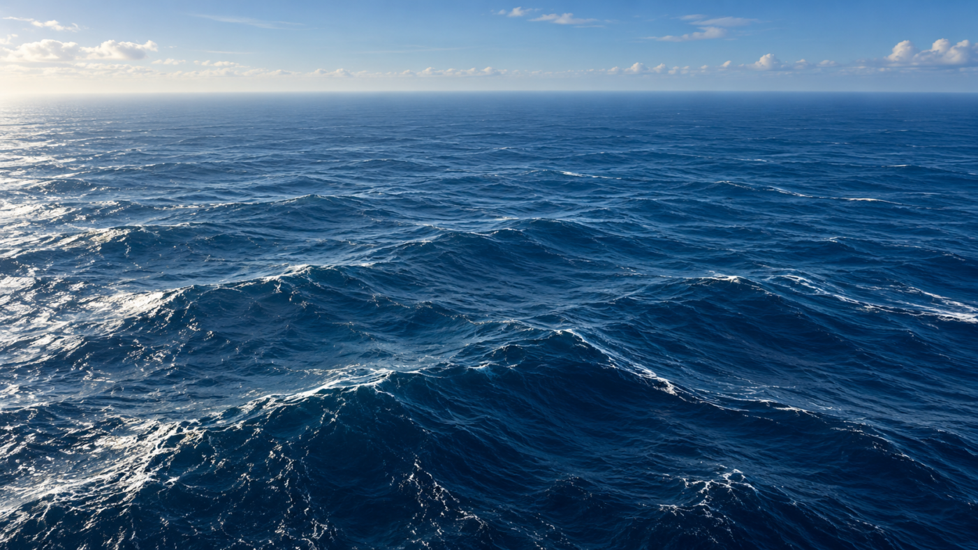 Vue aérienne de la pleine mer, houle longue et horizon vide, aucune côte ni navire en vue.